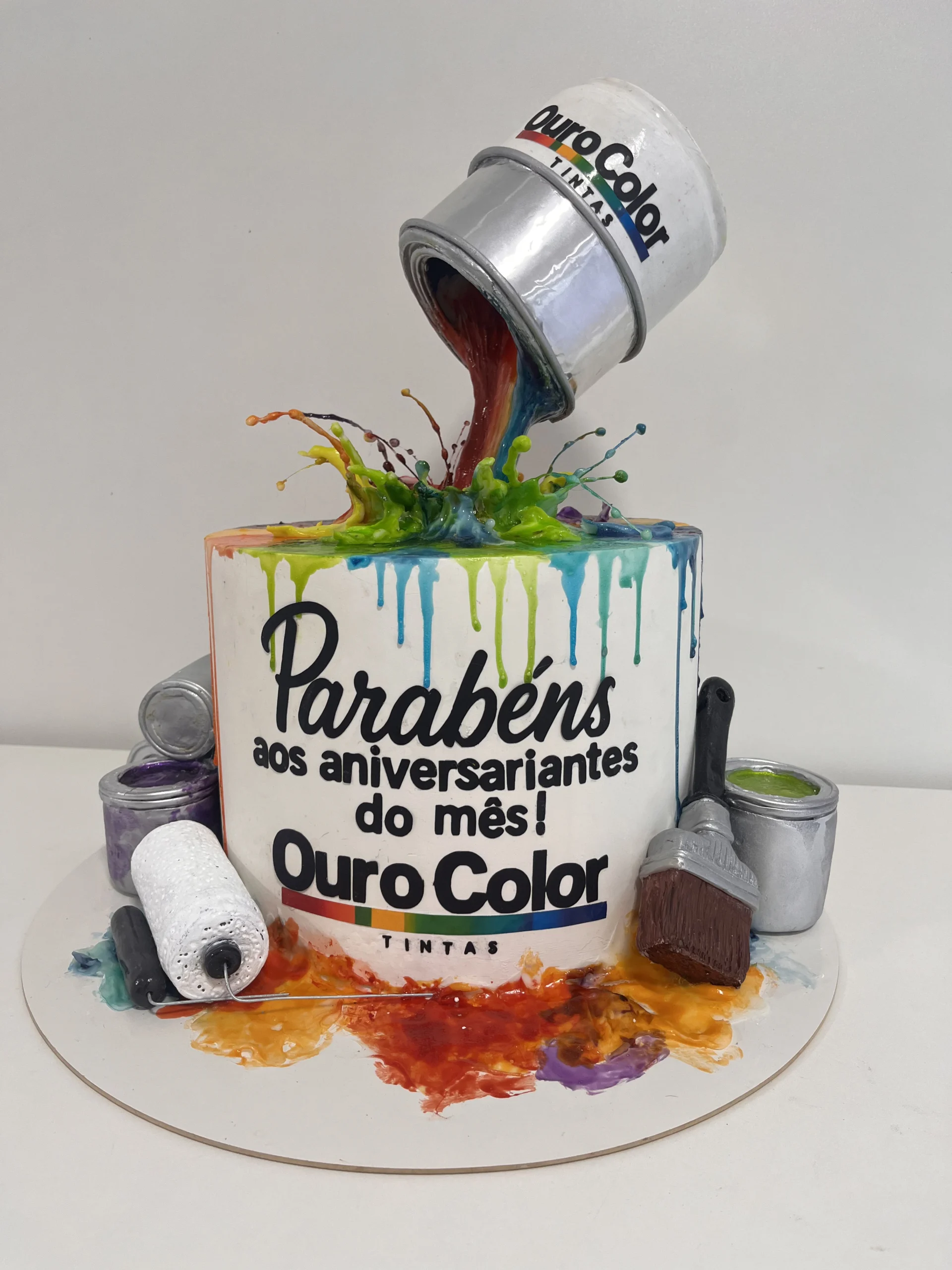 Bolo fake corporativo com lata de tinta derramando cores, personalizado para marca Ouro Color